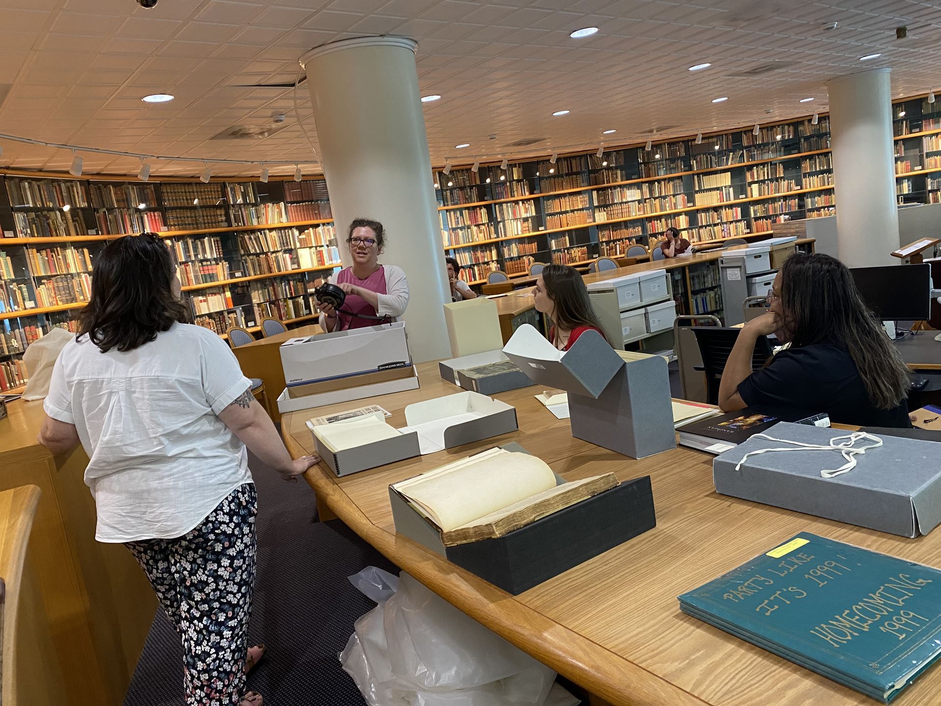 Randi Beem shows an object to a group of folks facing her in the UNCC reading room